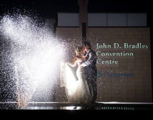 Couple dancing in front of building with water fountain